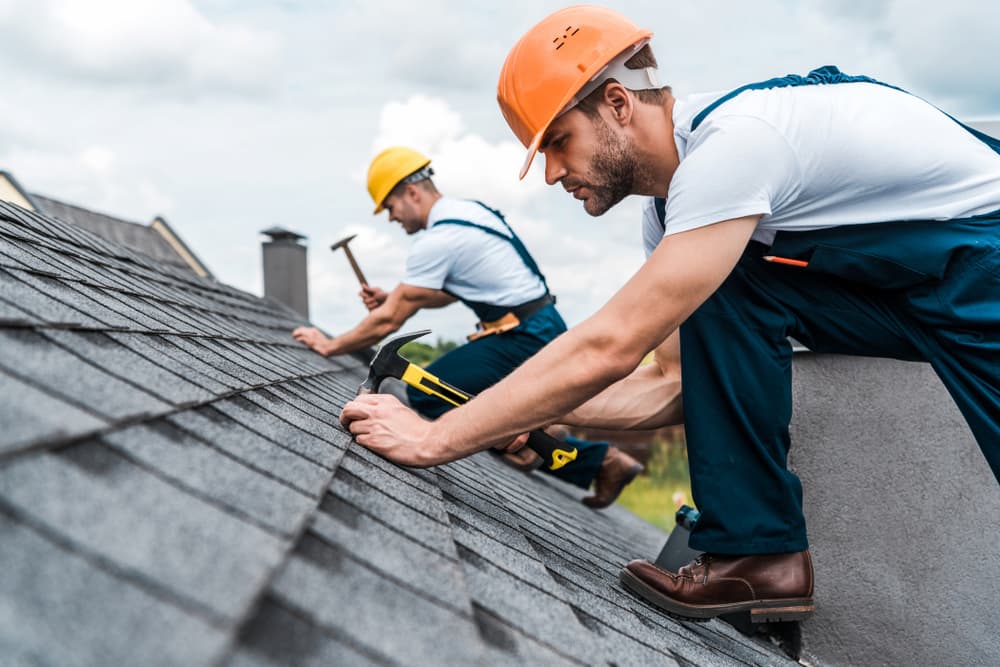 Two roof repair workers working on a roof